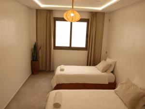 two beds in a room with a window at Tamraght Surf House in Tamraght Ouzdar