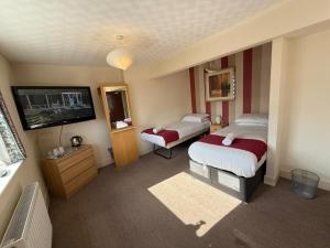 ein Hotelzimmer mit zwei Betten und einem Flachbildfernseher in der Unterkunft VERNON Hotel in Blackpool