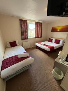 ein Hotelzimmer mit zwei Betten und einem Fenster in der Unterkunft VERNON Hotel in Blackpool