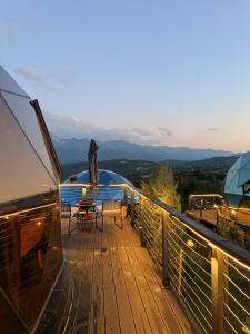 a wooden deck with a table and an umbrella at Bubble Sky Villas Kosove in Ferizaj