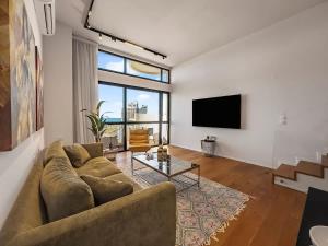 a living room with a couch and a flat screen tv at Beachfront Sky Loft in Herzliya B