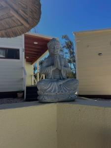 una statua di un monaco in preghiera seduto davanti a una casa di Cabañas San Jorge a Bella Vista