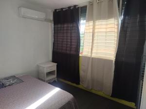 a bedroom with a bed and a window with curtains at Le regard sur la marina in Les Trois-Îlets