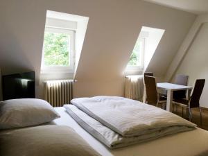 two beds in a room with a table and two windows at Old Town View in Cologne