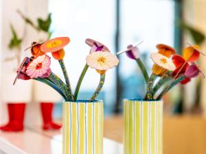 two vases with flowers in them on a table at Ibis Styles Strasbourg Centre République in Strasbourg