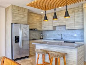 a kitchen with a stainless steel refrigerator and two bar stools at Spacious Pool Side Condo - SJD in San José del Cabo