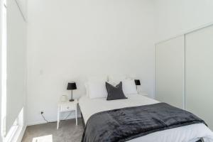 a white bedroom with a large bed with white walls at The Church House Luxe High Country Stay in Mount Beauty
