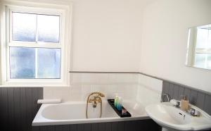 een badkamer met een ligbad en een wastafel bij The Channel View, 4 bedrooms, 4 beds, FREE parking, 3 minutes from the beach in Eastbourne +17 foto's