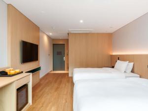 a hotel room with two beds and a flat screen tv at ibis Styles Ambassador Jeonju City Centre in Jeonju +48 photos