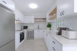 ブリスベンにあるSpacious 3-Bed Coorparoo Apartmentの白いキッチン(白いキャビネット、電化製品付)