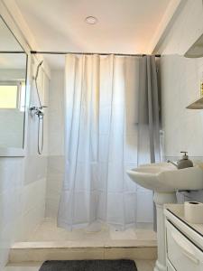 een witte badkamer met douche en wastafel bij Cozy Studio Apartment Maculusso, Luanda in Luanda