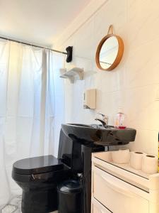 a bathroom with a black toilet and a sink at Cozy Studio Apartment Maculusso, Luanda in Luanda +53 photos