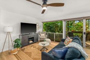 a living room with a blue couch and a tv at Modern Princeville 1 bedroom, AC, King Bed, Hanalei in Princeville