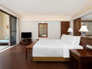 une chambre avec un grand lit blanc et une télévision dans l'établissement Swissôtel Sanya Yalong Bay, à Sanya