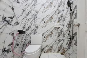 a bathroom with a white toilet and a marble wall at RedDoorz at Barra Homestay near RSUD Batang in Batang
