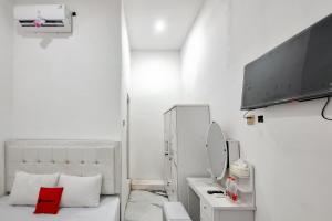 a white room with a bed and a television at RedDoorz at Barra Homestay near RSUD Batang in Batang