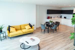 een woonkamer met een gele bank en een tafel bij Luxury 2 Bed apartment Deansgate in Manchester