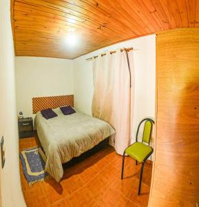 a small bedroom with a bed and a chair at Tu refugio en Caleta Olivia in Caleta Olivia
