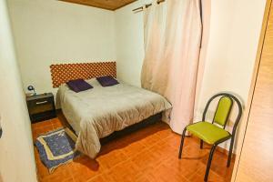 a small bedroom with a bed and a chair at Tu refugio en Caleta Olivia in Caleta Olivia