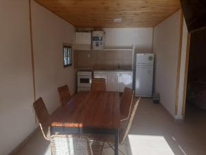 a kitchen with a wooden table and chairs and a refrigerator at Cabañas Pie del Plata in Mendoza