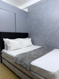 ein Bett mit weißen Kissen und einer Metallwand in der Unterkunft JA2 STAYCATION @TREES RESIDENCES in Manila