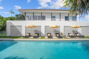 a house with a swimming pool with chairs and umbrellas at Your Own Luxury Coastal Beachfront Wellness Retreat 14 sleeps in Casuarina