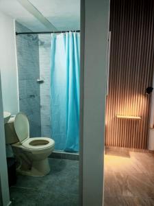 a bathroom with a toilet and a blue shower curtain at hotel Air b&b altos del peñon in Girardot +30 photos