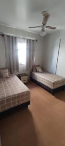 a bedroom with two beds and a ceiling fan at Apto 3 Quartos com Suíte e 3 Banheiros em Guarapari in Guarapari