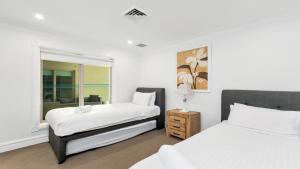 a bedroom with two beds and a window at Unit 2 - 3 Bedroom Part Ocean View in Terrigal +6 photos