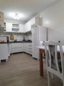 eine Küche mit weißen Schränken, einem Tisch und einem Kühlschrank in der Unterkunft Casa Amarela in Torres