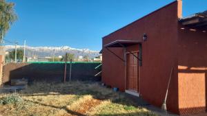 a red building with a door on the side of it at Aires de pedemonte mendocino in Las Heras