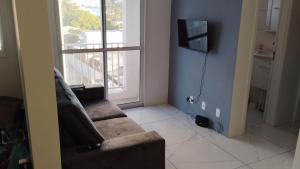 a living room with a couch and a large window at Apartamento Solar dos Pampas in Guaíba