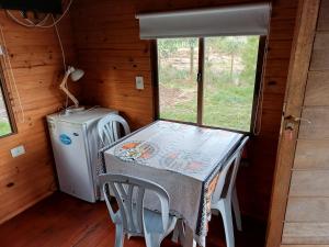 a table and chairs in a room with a refrigerator at Casa 1 Los Piamonteses 3 personas in Juan L. Lacaze
