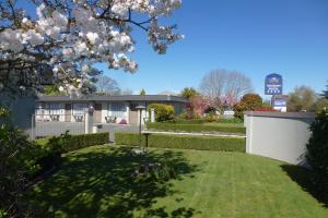 a house with a white fence and a yard at ASURE Adcroft Motel in Ashburton