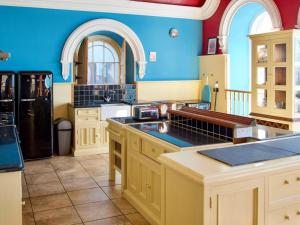 a large kitchen with blue walls and white cabinets at The Auction House in Criccieth