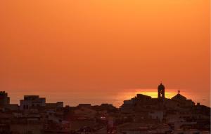 eine Skyline der Stadt mit einem Uhrturm bei Sonnenuntergang in der Unterkunft 4 Bedroom Awesome Apartment In Kaukana in Marina di Ragusa