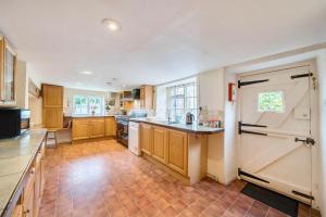 a large kitchen with wooden cabinets and a tile floor at Park Farmhouse in Chideock