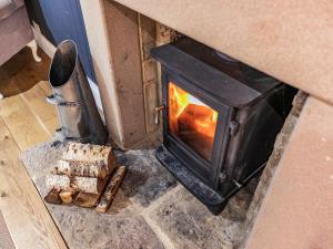 a wood stove with a fire in a room at South Carolina Farm House in Tansley