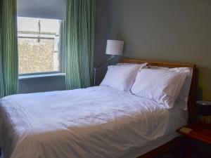 a bedroom with a bed with white sheets and a window at Blackbird House in Alnwick