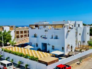 Un edificio blanco con un coche rojo aparcado delante. en Dolphina hotel & Restaurant, en Dahab 92 fotos más