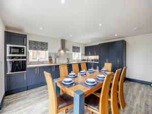 a kitchen with a wooden table and blue cabinets at Cowslip Cottage - Uk47072 in Maltby le Marsh