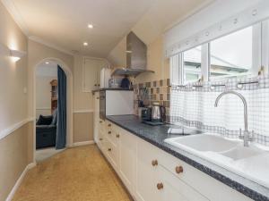 een keuken met een spoelbak en een raam bij St Elmo Lodge - Cottage in Salcombe