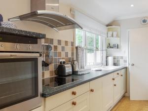 een keuken met een fornuis bovenste oven naast een raam bij St Elmo Lodge - Cottage in Salcombe