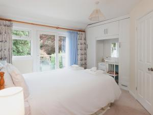 een witte slaapkamer met een groot wit bed en ramen bij St Elmo Lodge - Cottage in Salcombe