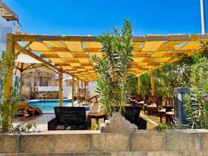 a wooden pergola with chairs and tables and a pool at Dolphina hotel & Restaurant in Dahab