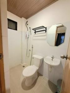 a white bathroom with a toilet and a sink at Scyldric Apartelle in El Nido