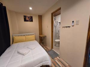 a bedroom with a large white bed and a bathroom at Scyldric Apartelle in El Nido