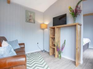 a living room with a couch and a television at Moor Hen Shepherd Hut - Uk33888 in Cullompton