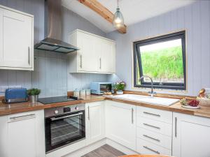 a kitchen with white cabinets and a sink and a window at Moor Hen Shepherd Hut - Uk33888 in Cullompton +11 photos