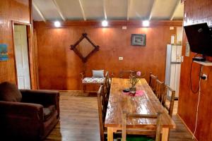 - une salle à manger avec une table en bois et un canapé dans l'établissement Cabaña Parcela Nativo, à Los Álamos
